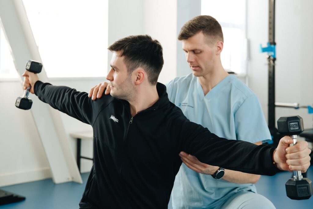 Man Supporting Patient who Lifting Dumbbells - physiotherapy Belgium